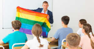 Male teacher holding rainbow flag Sex workers and gender diverse face working with children discrimination